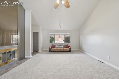 Living room featuring carpet flooring, ceiling fan, lofted ceiling, and baseboards