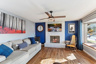 Living area featuring laminate finished floors, a fireplace, and a ceiling fan