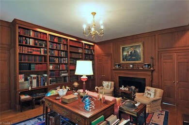 Wood paneled library with floor to ceiling built-in bookcases and fireplace