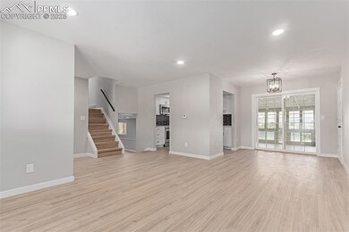 Unfurnished living room featuring stairway, a chandelier, baseboards, light wood-type flooring, and recessed lighting