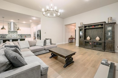 Living area featuring light wood-style flooring, a chandelier, and recessed lighting