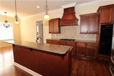 Don't you just love the rich feel of these wood cabinets? This kitchen is open to the family room so your guests will feel right at home.