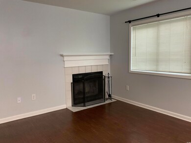 Unfurnished living room featuring wood finished floors and a tiled fireplace