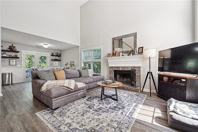 Living room featuring wood finished floors, french doors, a brick fireplace, and a towering ceiling