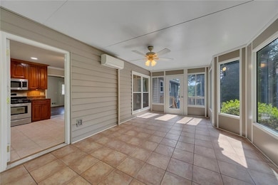 Unfurnished sunroom featuring ceiling fan, a wall unit AC, and french doors