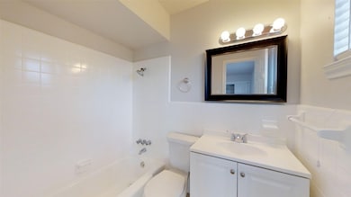 Bathroom with vanity, shower / washtub combination, tile walls, and wainscoting