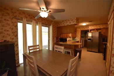 Dining room featuring wallpapered walls, light colored carpet, a textured ceiling, and a ceiling fan