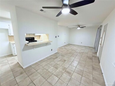 Empty room with a ceiling fan and light tile patterned flooring