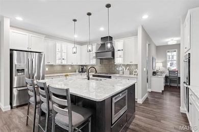 Kitchen with stainless steel appliances, decorative backsplash, white cabinetry, and recessed lighting