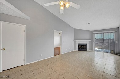 Unfurnished living room featuring a textured ceiling, light tile patterned floors, a fireplace, a ceiling fan, and high vaulted ceiling