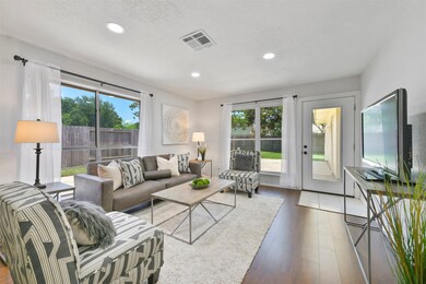 An alternate view of the family room highlights the abundance of windows with natural sunlight filtering into the space. A full-panel glass door at the rear leads to the covered breezeway, the detached 2-car garage, and the back patio.
