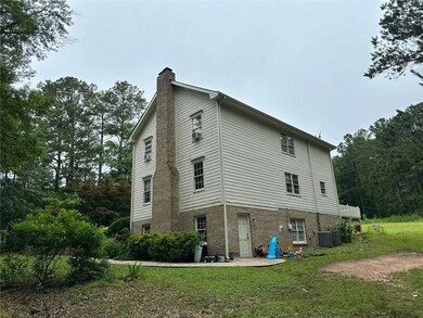View of side of property featuring a chimney, a yard, and brick siding