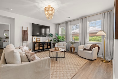 Living room with wood finished floors, a chandelier, and baseboards