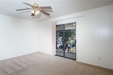 Carpeted empty room with a ceiling fan and baseboa
