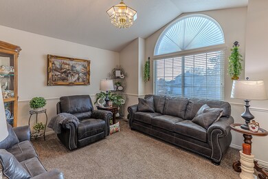 Living area with lofted ceiling, carpet flooring, and a chandelier