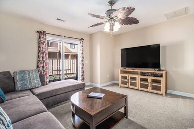 Carpeted living room with a ceiling fan and basebo