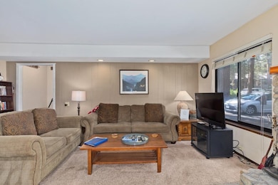 Living room featuring light colored carpet, wood walls, and recessed lighting