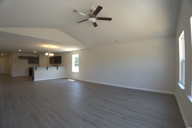 Unfurnished living room with vaulted ceiling, a chandelier, dark wood-style floors, and a ceiling fan