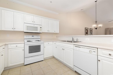 Kitchen with white appliances, a sink, light tile 