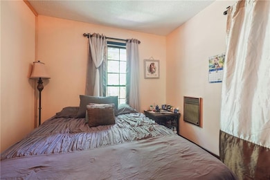 Bedroom featuring a textured ceiling and heating unit