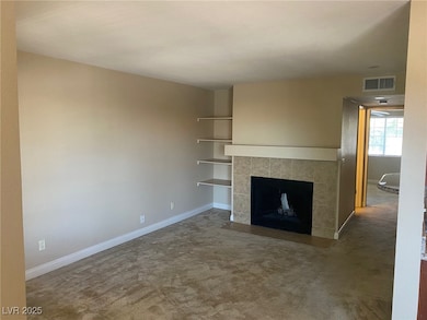 Unfurnished living room featuring a tile fireplace and carpet flooring