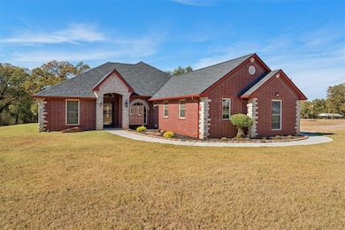 View of front facade featuring brick siding, a front yard, and roof with shingles