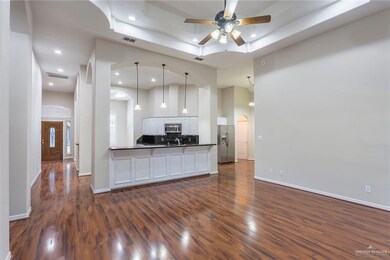 Unfurnished living room with a ceiling fan, dark wood finished floors, a raised ceiling, recessed lighting, and arched walkways