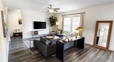 Living room with ceiling fan and dark wood-type fl