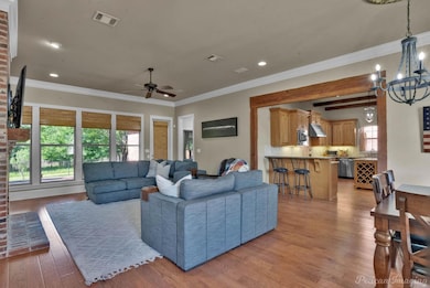 Living room featuring crown molding, light wood fi