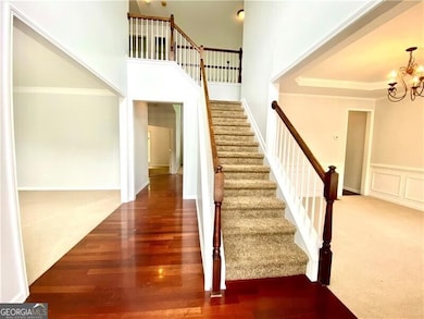 Stairs with a chandelier, ornamental molding, wood finished floors, a tray ceiling, and carpet flooring