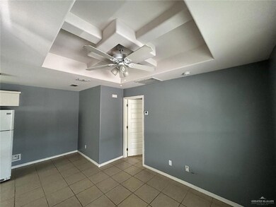 Empty room featuring a tray ceiling, ceiling fan, baseboards, and dark tile patterned floors