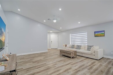 Living room featuring vaulted ceiling, light wood-