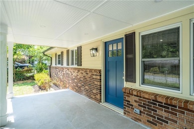 View of exterior entry featuring brick siding and a porch