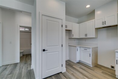 Kitchen with white cabinetry, light countertops, l