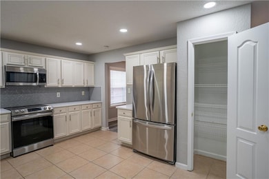 Kitchen featuring appliances with stainless steel finishes, light tile patterned floors, light countertops, decorative backsplash, and recessed lighting