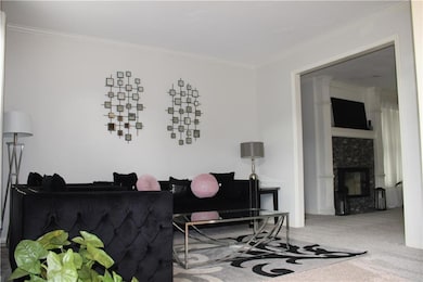 Living area with carpet, ornamental molding, and a fireplace