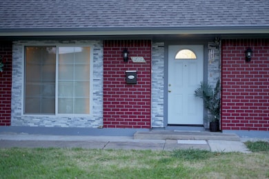 Doorway to property featuring brick siding and a s
