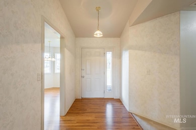 Foyer entrance with wood finished floors, wallpapered walls, and a chandelier