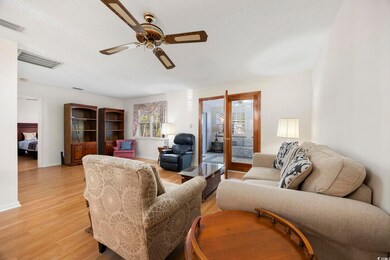 Living area with visible vents, ceiling fan, baseb