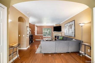 Living room featuring arched walkways, wood-type flooring, ornamental molding, and a tiled fireplace