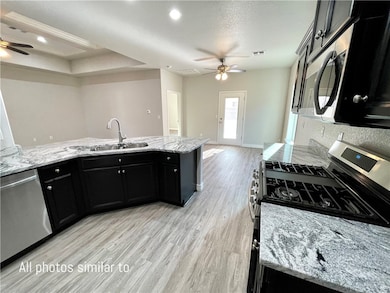 Kitchen featuring a sink, ceiling fan, dark cabine