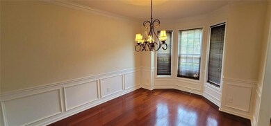 Unfurnished dining area with a chandelier, ornamental molding, a wainscoted wall, dark wood-type flooring, and a decorative wall