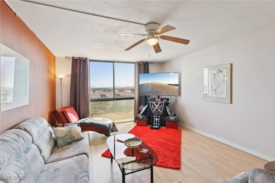 Living area with a ceiling fan, a wall of windows,