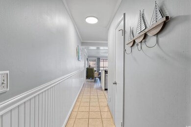 Hallway with crown molding and light tile patterned floors