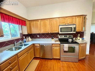 Kitchen with stainless steel appliances, a sink, light wood-style floors, and decorative tile backsplash