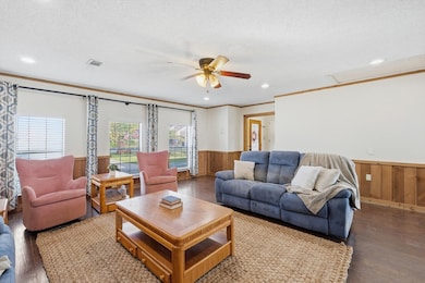 Living room with hardwood / wood-style flooring, ornamental molding, a ceiling fan, recessed lighting, and wood walls