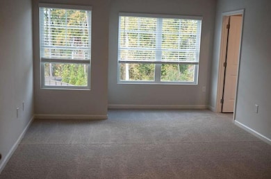 Empty room featuring light carpet and baseboards