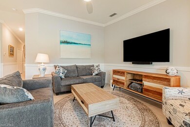 Living area featuring ornamental molding, light tile patterned floors, a ceiling fan, and wainscoting