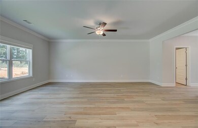 Empty room featuring a ceiling fan, ornamental molding, light wood-style flooring, and baseboards