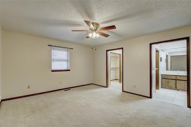 Carpeted empty room with a ceiling fan and a textured ceiling
